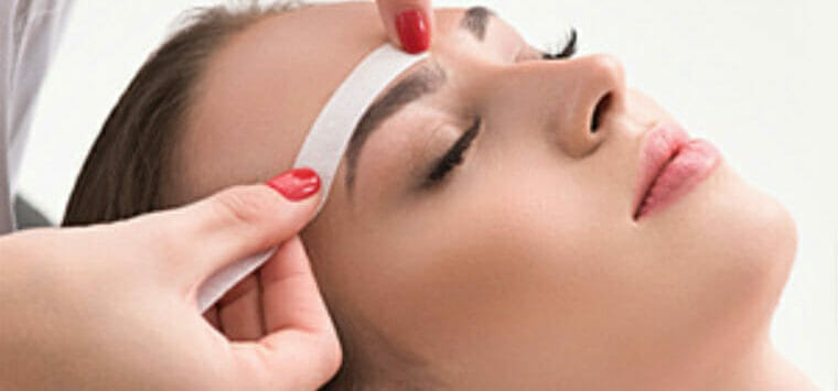 Woman receiving brow shaping services on her eyebrows.