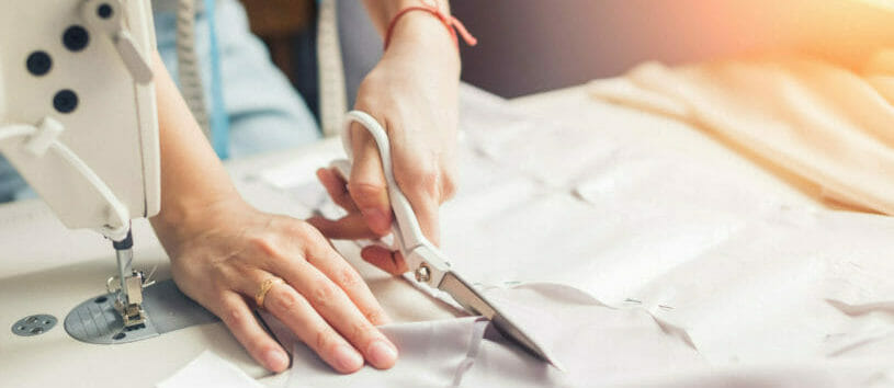 Person cutting a piece of fabric before using it for sewing.