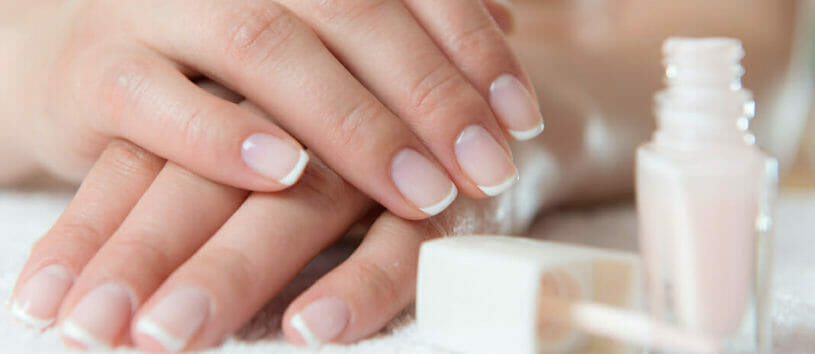 Freshly manicured fingernails with nail polish next to them.