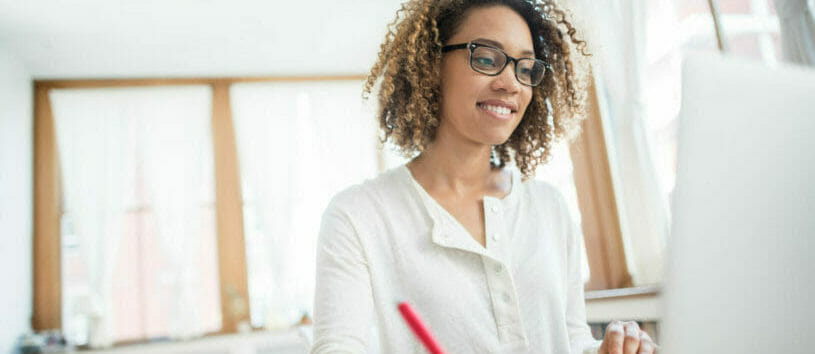 Young African American business woman working at home on a laptop computer and wearing glasses