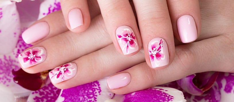 Fingernails with pink nail polish and flower design.